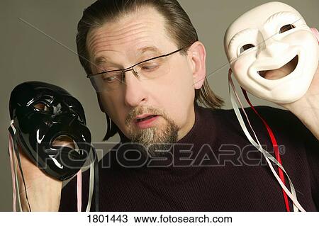 Stock Image - Man holding happy and sad mask. Fotosearch