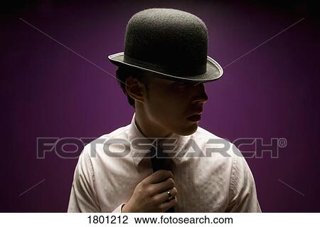 Stock Image - Man in top hat holding tie. Fotosearch
