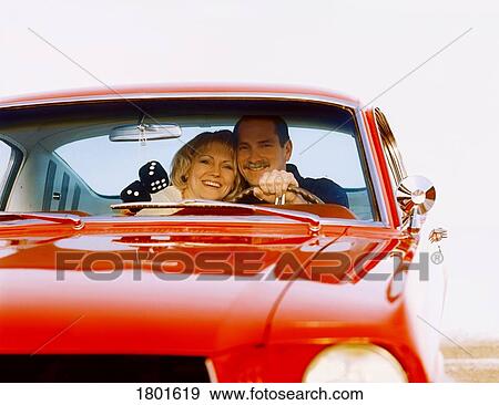 Stock Photo - Middle aged couple in front seat of red car. Fotosearch