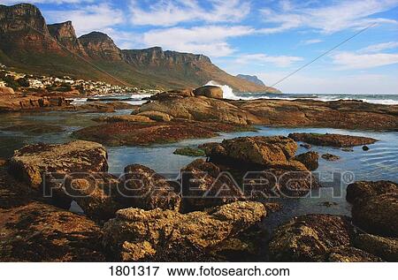 Stock Photo - Rocky seashore with mountainous background. Fotosearch