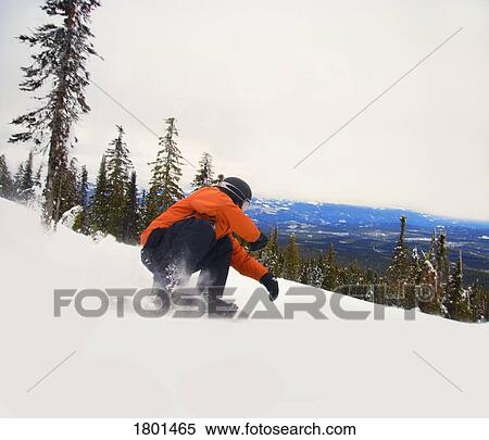 Snowboarder crouching down low as he descends snow hill View Large Photo Image Stock Photography - Snowboarder crouching down low as he descends snow hill. Fotosearch