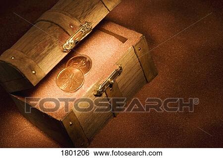 Stock Photograph - Treasure chest in the sand with coins in it. Fotosearch