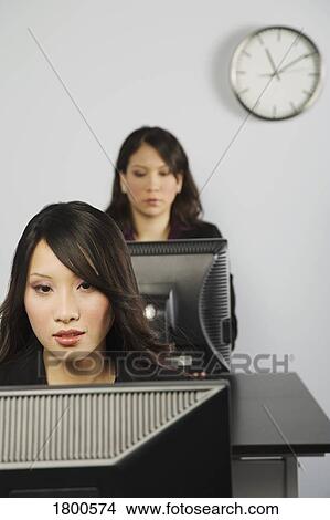 Picture - Two women in office working at computers. Fotosearch