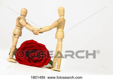 Stock Photography - Two wooden dummies holding hands over a large rose. Fotosearch