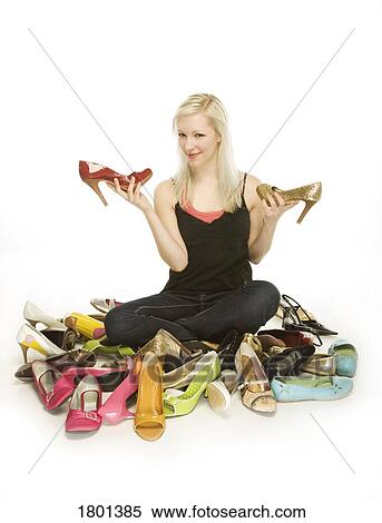 Woman sitting in pile of shoes while holding two high heeled shoes View Large Photo Image Stock Photography - Woman sitting in pile of shoes while holding two high heeled shoes. Fotosearch