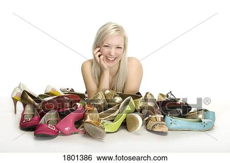 Stock Photograph - Woman smiling with pile of shoes in front of her. Fotosearch