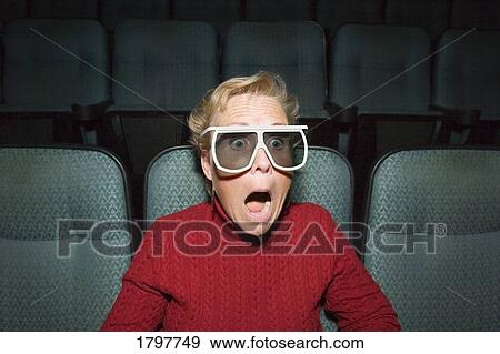 Woman with a shocked expression at a movie theater View Large Photo Image Stock Photo - Woman with a shocked expression at a movie theater. Fotosearch