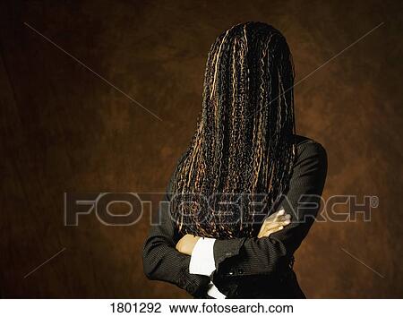 Stock Image - Woman with hair covering her face and arms crossed. Fotosearch
