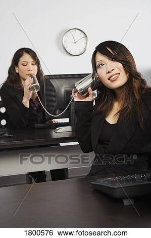 Stock Photograph - Women talking into cans as phone. Fotosearch