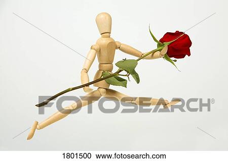 Stock Image - Wooden doll holding a red rose . Fotosearch