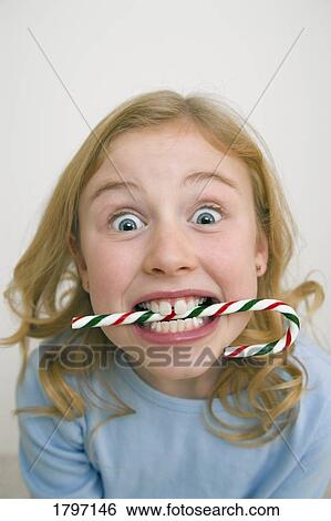 Young girl holding a candy cane between her teeth View Large Photo Image Stock Photograph - Young girl holding a candy cane between her teeth. Fotosearch