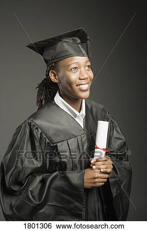 Stock Photograph - Young Woman in cap and gown with diploma. Fotosearch