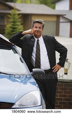 Stock Image - A businessman standing by car. Fotosearch