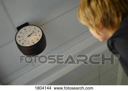 Picture - A child looking at a clock. Fotosearch