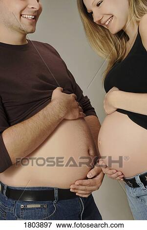 Stock Photo - A couple comparing bellies. Fotosearch