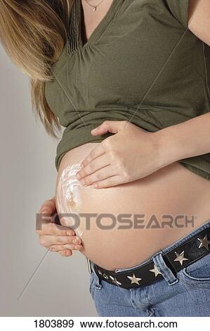 A pregnant woman applying cream on her belly View Large Photo Image Stock Photo - A pregnant woman applying cream on her belly. Fotosearch