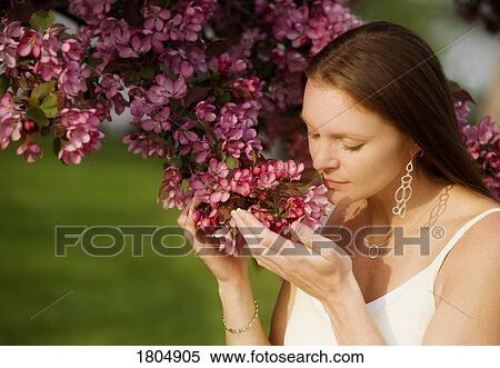 Stock Photography - A young woman smelling flowers. Fotosearch