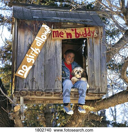 Stock Image - Boy hanging out in treehouse with dog. Fotosearch