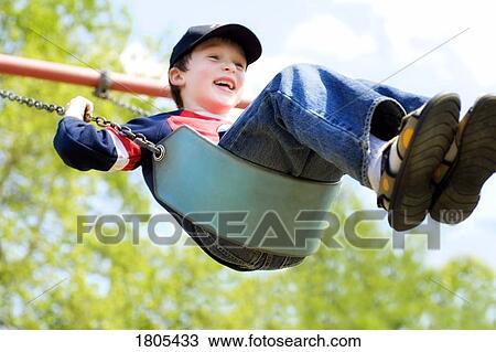Stock Image - Boy smiling on swing. Fotosearch