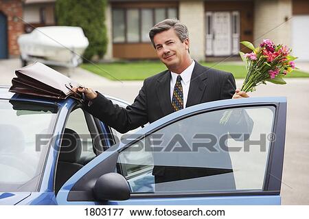 Businessman holding bouquet, smiling View Large Photo Image Stock Photo - Businessman holding bouquet, smiling. Fotosearch