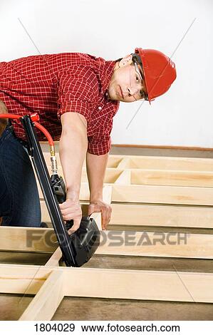 Stock Photo - Carpenter working with nail gun. Fotosearch