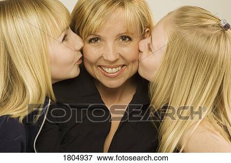 Stock Photo - Daughters kissing their mother on the cheek. Fotosearch