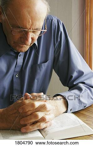 Elderly man praying with the Bible View Large Photo Image Stock Image - Elderly man praying with the Bible. Fotosearch