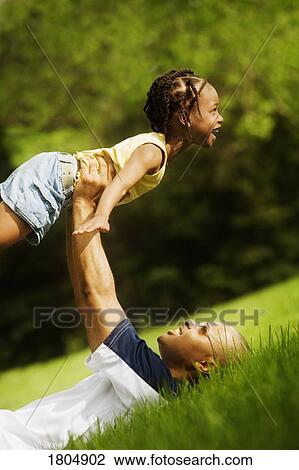 Father lifting his daughter in the park View Large Photo Image Stock Image - Father lifting his daughter in the park. Fotosearch
