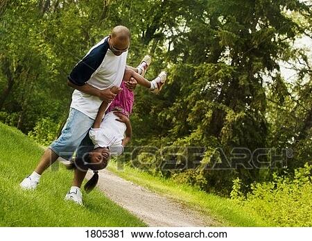 Stock Image - Father playing with daughter in park. Fotosearch