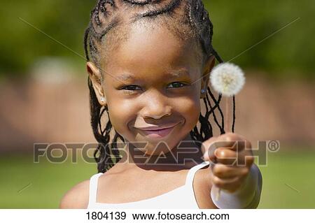 Stock Photo - Girl holding a dandelion and smiling. Fotosearch