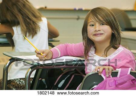 Girl sitting at her desk in the classroom View Large Photo Image Stock Photo - Girl sitting at her desk in the classroom. Fotosearch