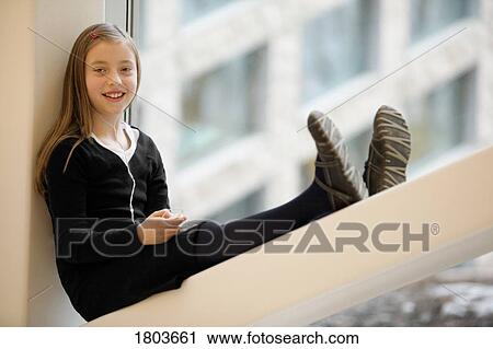 Stock Image - Girl sitting on window, smiling. Fotosearch