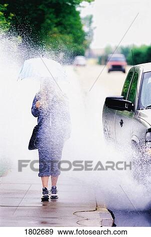 Stock Photo - Girl splashed with water by car driving by. Fotosearch