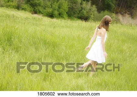 Stock Image - Girl walking through long grass. Fotosearch