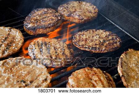 Stock Image - Hamburger patties cooking on the grill . Fotosearch