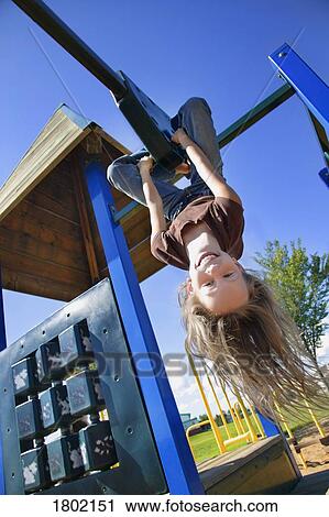 Little girl hanging upside down on playground equipment View Large Photo Image Stock Image - Little girl hanging upside down on playground equipment. Fotosearch