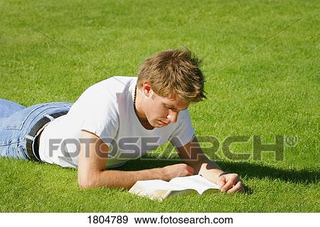 Stock Photo - Man reading book on the grass. Fotosearch
