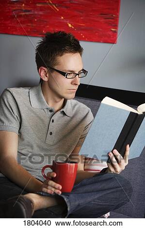 Stock Image - Man reading with a hot drink. Fotosearch