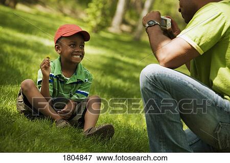 Stock Photo - Man taking a picture of his son. Fotosearch