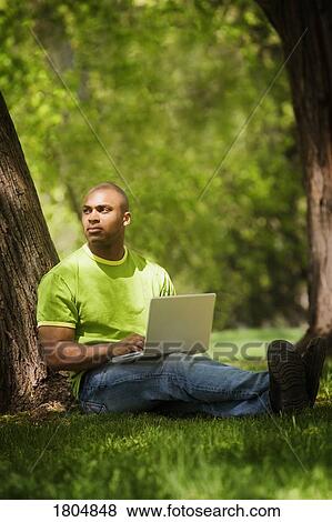 Stock Photo - Man using a laptop in the park. Fotosearch
