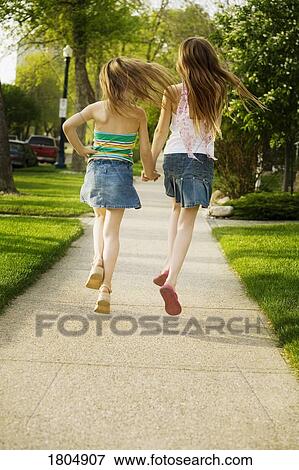 Rear view of girls running on sidewalk View Large Photo Image Stock Photo - Rear view of girls running on sidewalk. Fotosearch