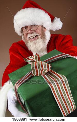 Stock Image - Santa Claus holding a gift. Fotosearch
