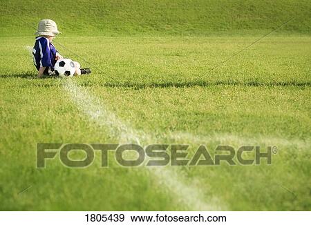 Side view of boy sitting with football View Large Photo Image Stock Photo - Side view of boy sitting with football. Fotosearch