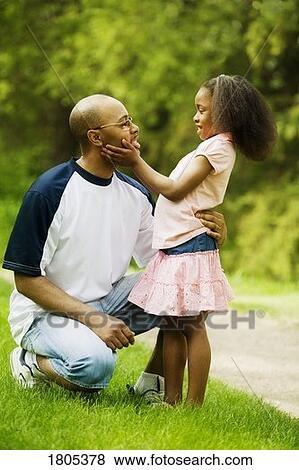 Stock Photo - Side view of father with daughter in park. Fotosearch