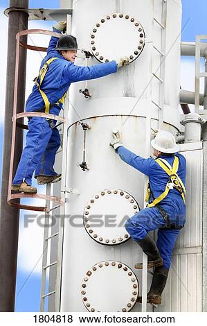 Stock Photo - Side view of two industrial workers on ladders. Fotosearch