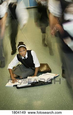 Stock Photo - Teenage girl doing homework in middle of school hall. Fotosearch