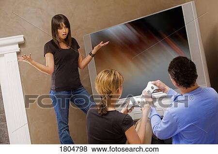 Teenage girl frustrated with couple for playing video games View Large Photo Image Stock Photo - Teenage girl frustrated with couple for playing video games. Fotosearch