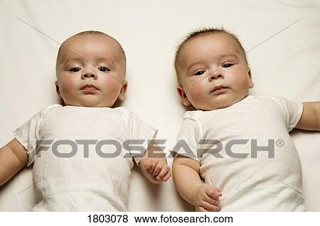 Two babies lying on a bed View Large Photo Image Stock Photo - Two babies lying on a bed. Fotosearch