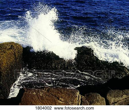 Stock Image - Waves crashing on rocky beach. Fotosearch