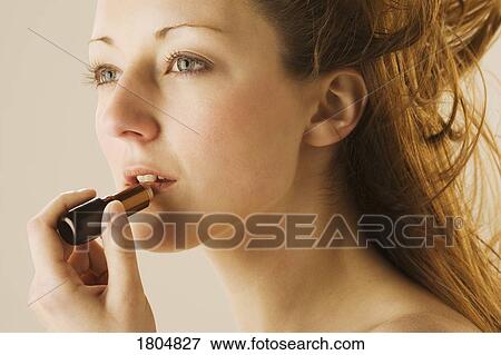 Woman applying lipstick View Large Photo Image Stock Photo - Woman applying lipstick. Fotosearch
